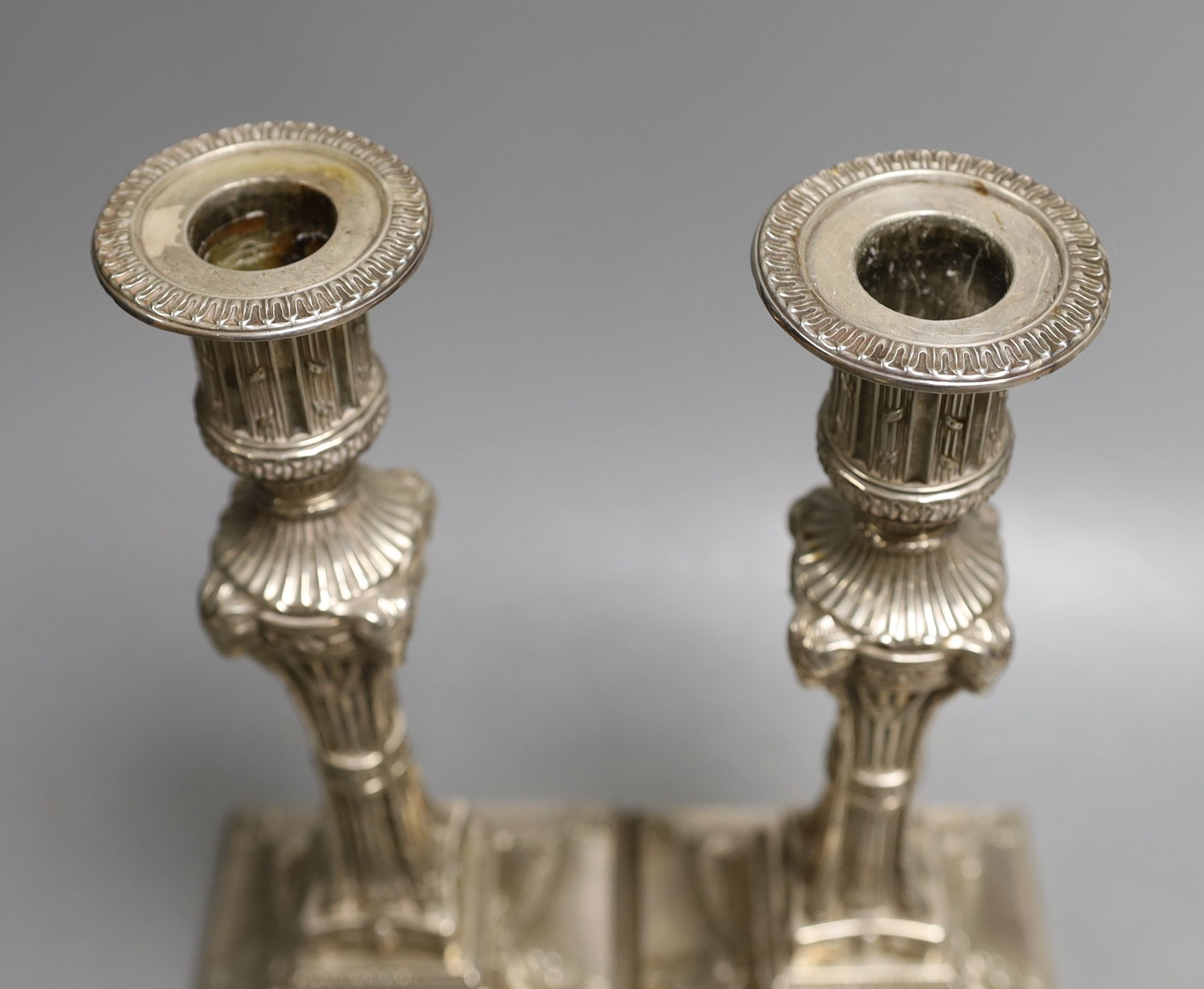 A matched pair of George III silver candlesticks, with waisted fluted stems and rams head, winged mask and swag decoration, Joseph Tibbitts, Sheffield, 1775 and George Ashforth & Co, Sheffield, 1775 29.4cm, weighted.